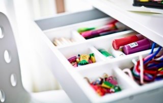 A close-up of a desk drawer with a cutlery tray from IKEA inside.