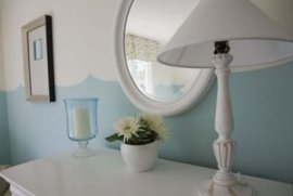 A well placed lamp, potted plant and candle frame a small round mirror attractively, eliminating empty space.