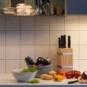 Well-lit countertop filled with different colored vegetables and kitchen accessories.