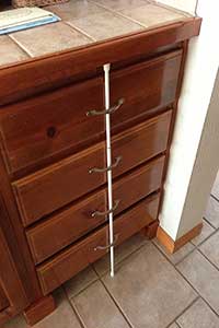 Tension rod pressed up against drawers to keep children out
